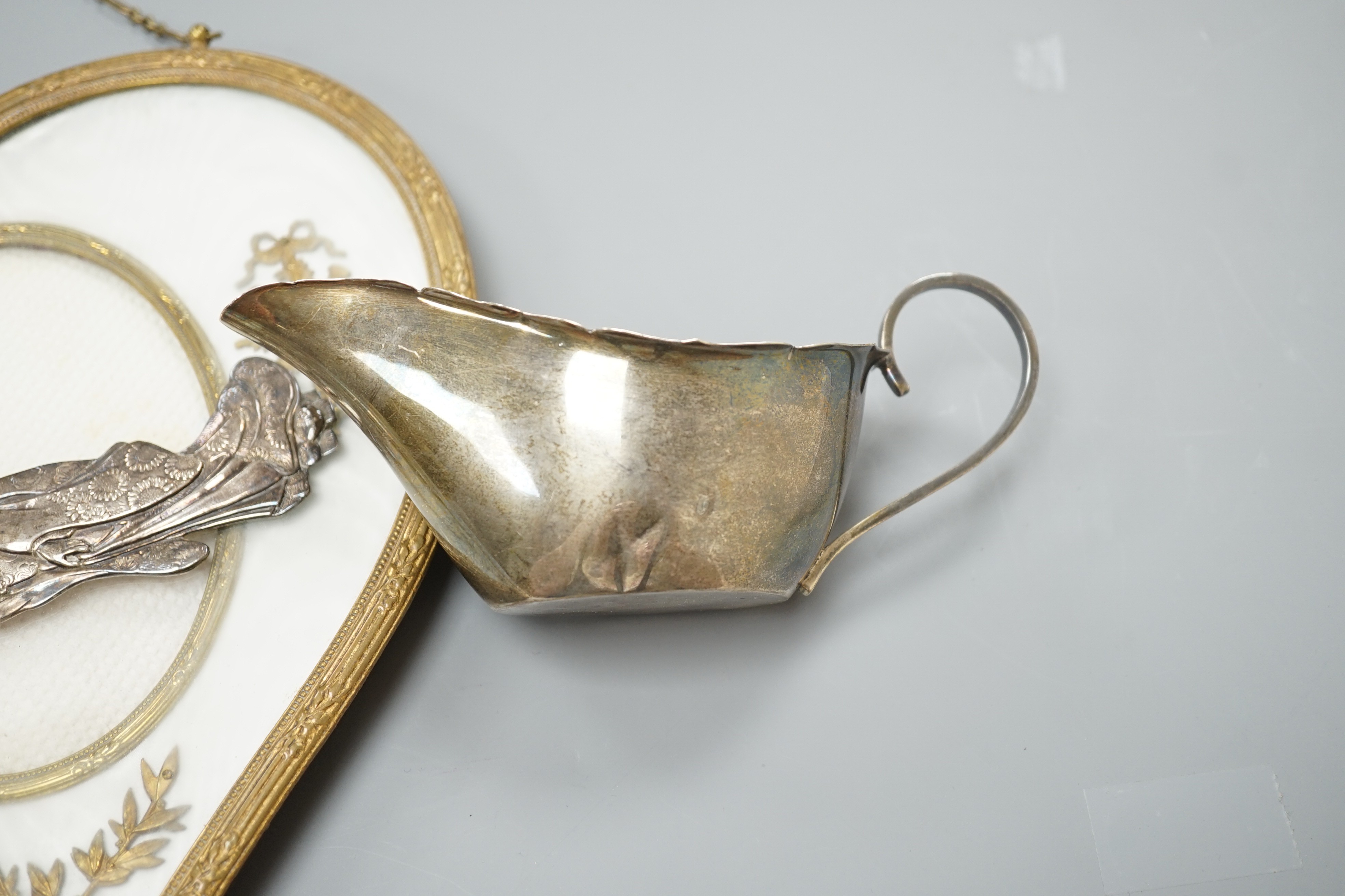 A 19th century gilt heart-shaped frame, A Japanese sterling figural spoon, a 1930's silver cream jug and modern silver mounted clock, photo frame 20 cms high.